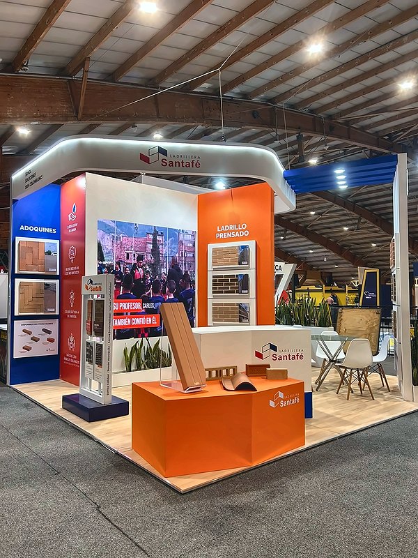 Stand para feria con counter naranja, exhibición de producto y mobiliario